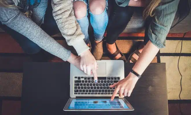 three person pointing the silver laptop computer