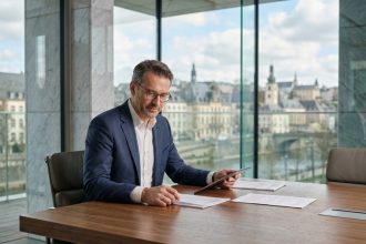 Conseiller en gestion de patrimoine analysant des documents financiers dans un bureau bancaire luxembourgeois moderne